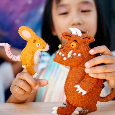 Child holding two felt toys, a mouse and a creature, with a colorful background. Stockists of Tara Treasures at Zebra Finch in Newcastle, NSW