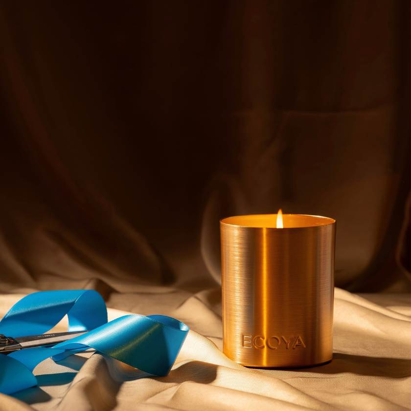 Bronze candle holder with a lit candle on a brown fabric background