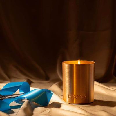 Bronze candle holder with a lit candle on a brown fabric background