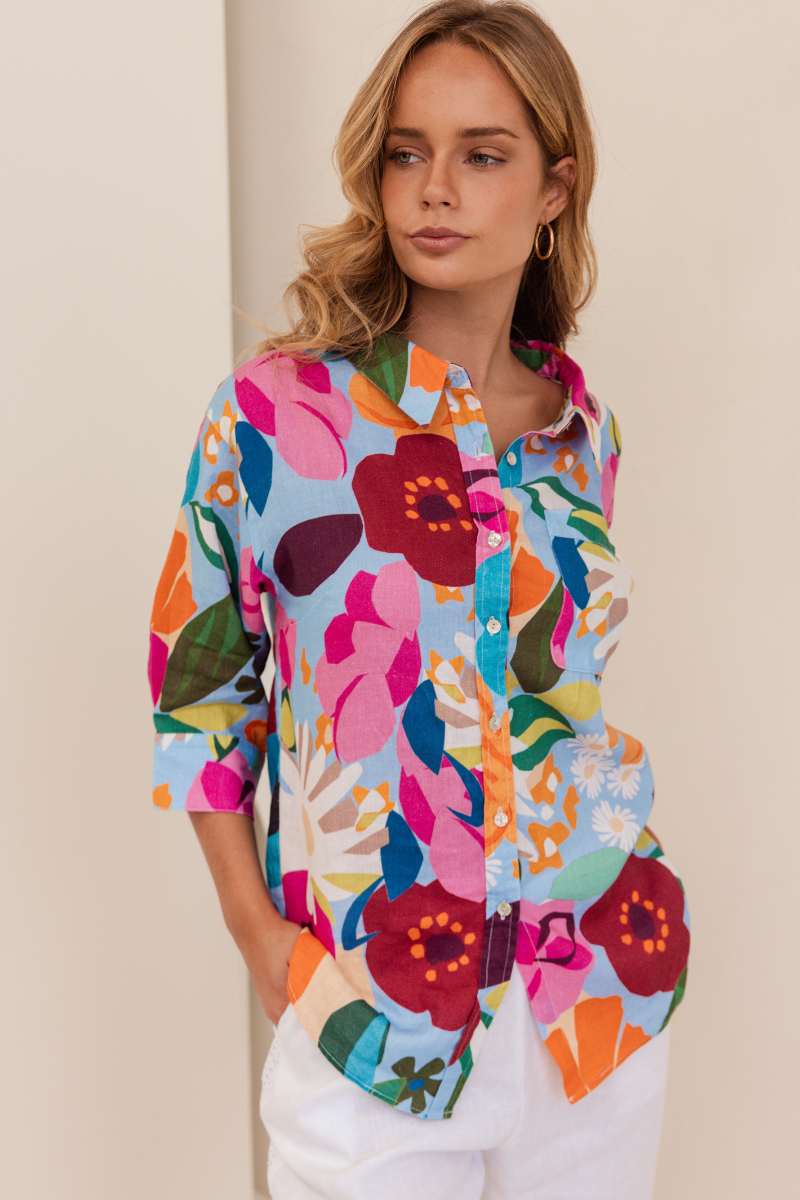 Woman wearing a colourful floral shirt against a beige background. Shirt by Kaleido - Kaleido Stockist at Zebra Finch in Newcastle, NSW