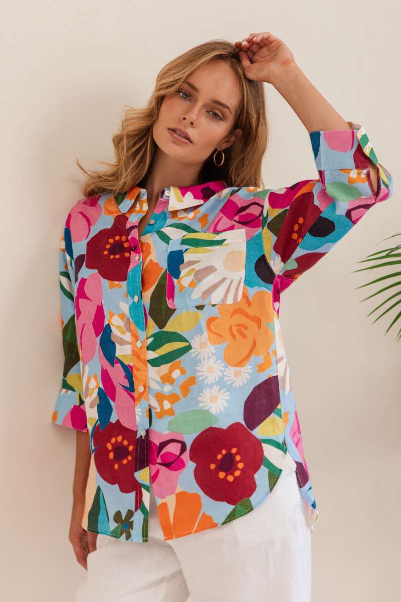 Woman wearing a colourful floral shirt against a beige background. Shirt by Kaleido - Kaleido Stockist at Zebra Finch in Newcastle, NSW