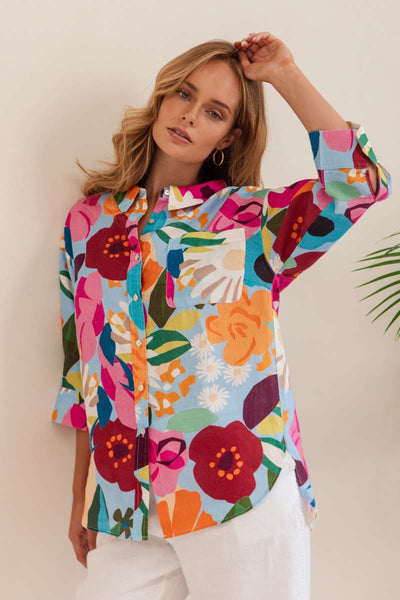 Woman wearing a colourful floral shirt against a beige background. Shirt by Kaleido - Kaleido Stockist at Zebra Finch in Newcastle, NSW
