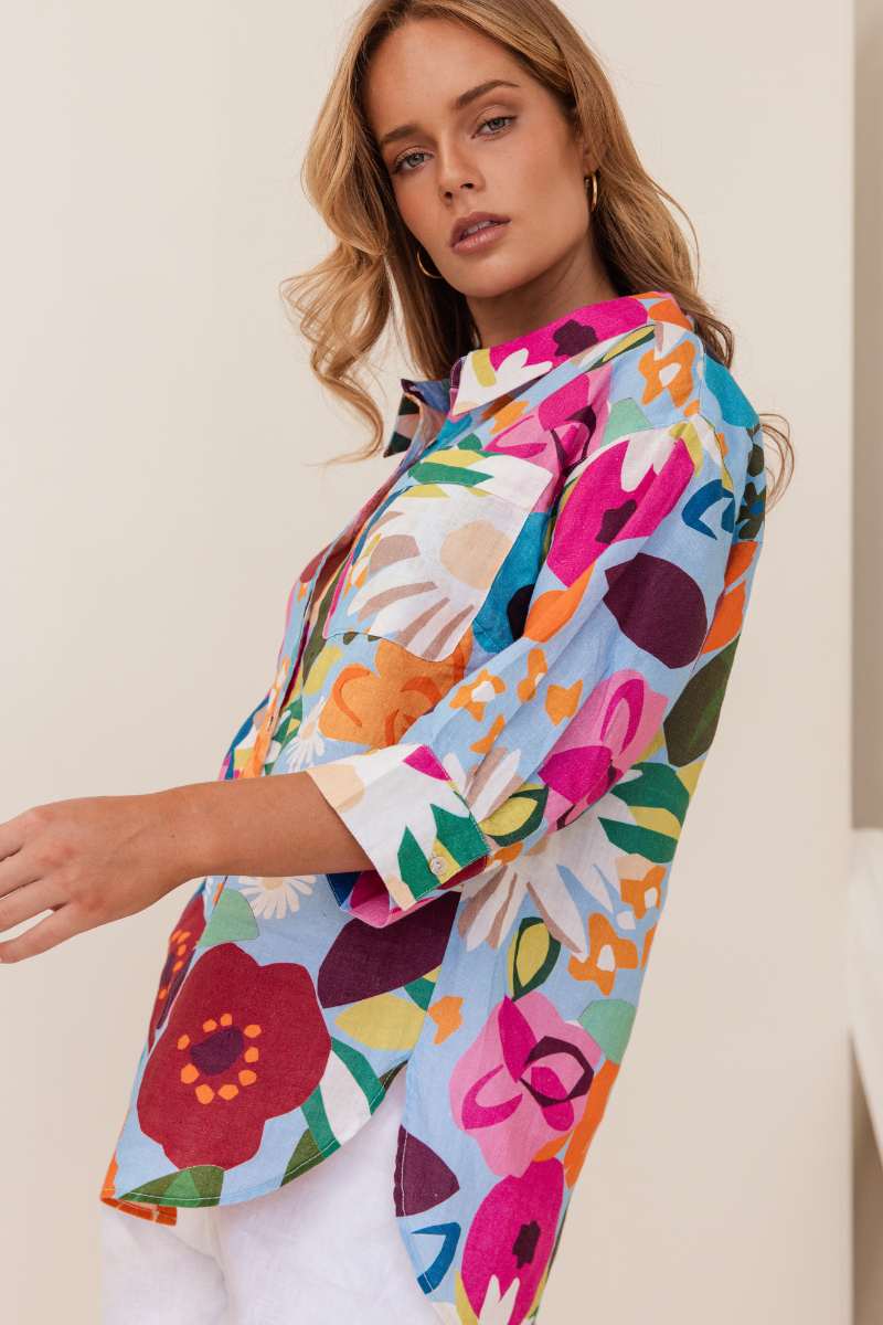 Woman wearing a colourful floral shirt against a beige background. Shirt by Kaleido - Kaleido Stockist at Zebra Finch in Newcastle, NSW