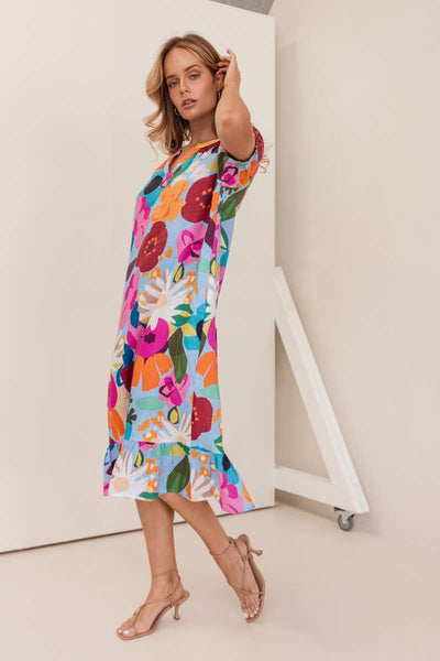 Woman wearing a colourful floral dress against a plain background. Dress by Kaleido. Kaleido Stockist in Newcastle, NSW at Zebra Finch