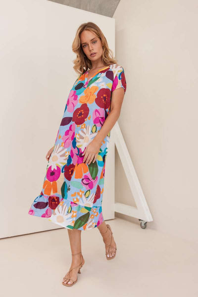 Woman wearing a colourful floral dress against a plain background. Dress by Kaleido. Kaleido Stockist in Newcastle, NSW at Zebra Finch