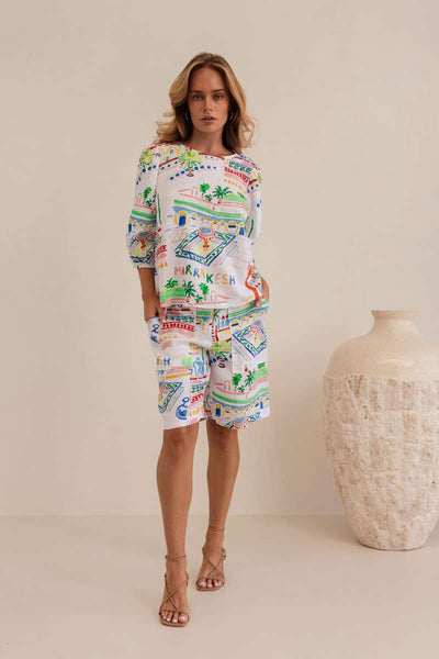 Woman wearing a colorful patterned dress against a beige background by Kaleido