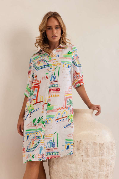 Woman wearing a colourful patterned dress against a neutral background, dress by Kaleido