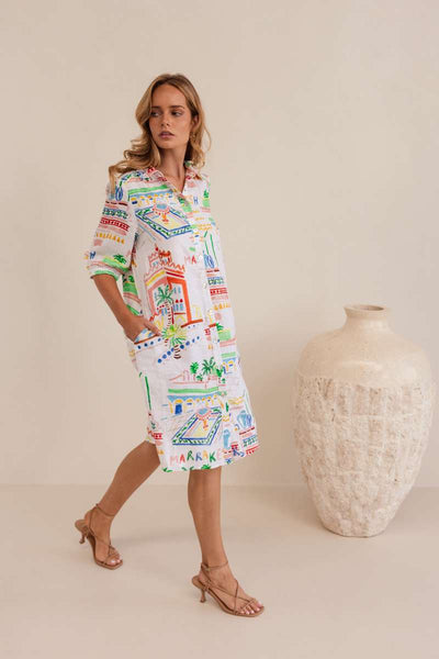 Woman wearing a colourful patterned dress against a neutral background, dress by Kaleido