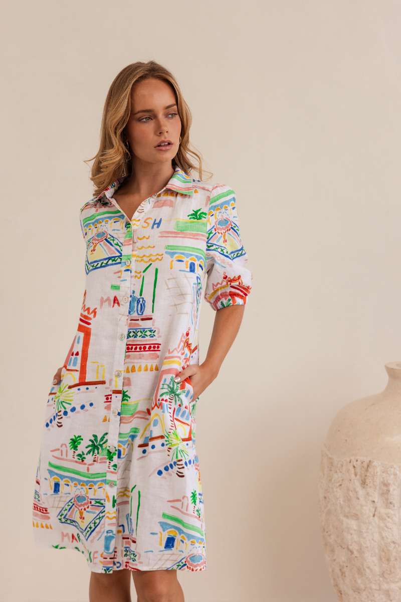 Woman wearing a colourful patterned dress against a neutral background, dress by Kaleido