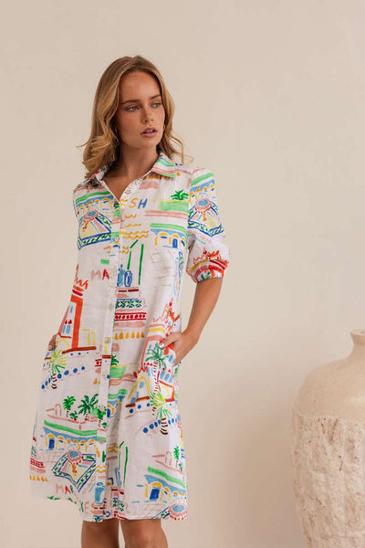 Woman wearing a colourful patterned dress against a neutral background, dress by Kaleido