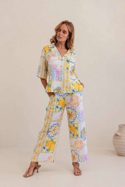 Woman wearing a colourful floral blouse against a plain background, by Kaliedo