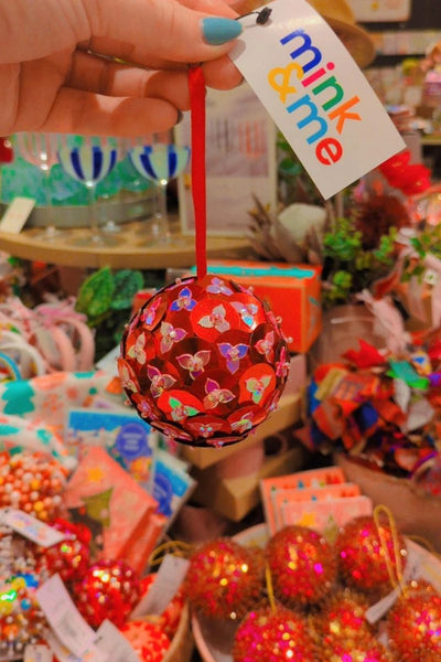 Decorative ball with geo pattern held by a hand, with 'minke' tag in a colorful setting.