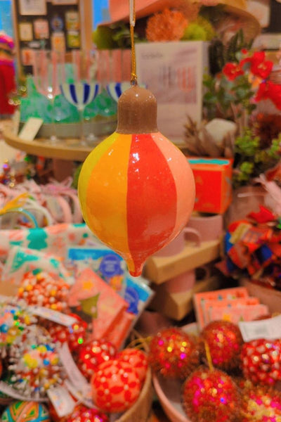 Decorative orange and yellow striped ball in a store setting with various items.