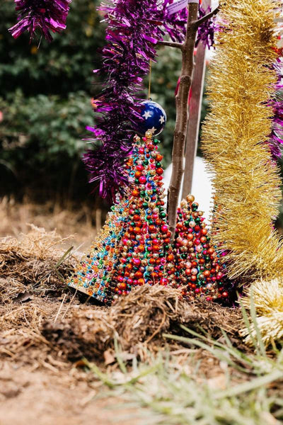 Colorful beaded Christmas tree with tinsel and purple decorations on a natural background