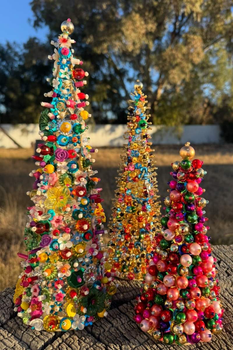 Colorful beaded Christmas trees on a wooden surface with a natural background