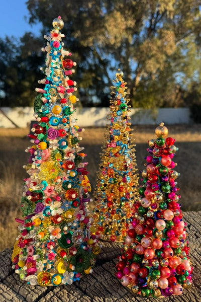 Colorful beaded Christmas trees on a wooden surface with a natural background