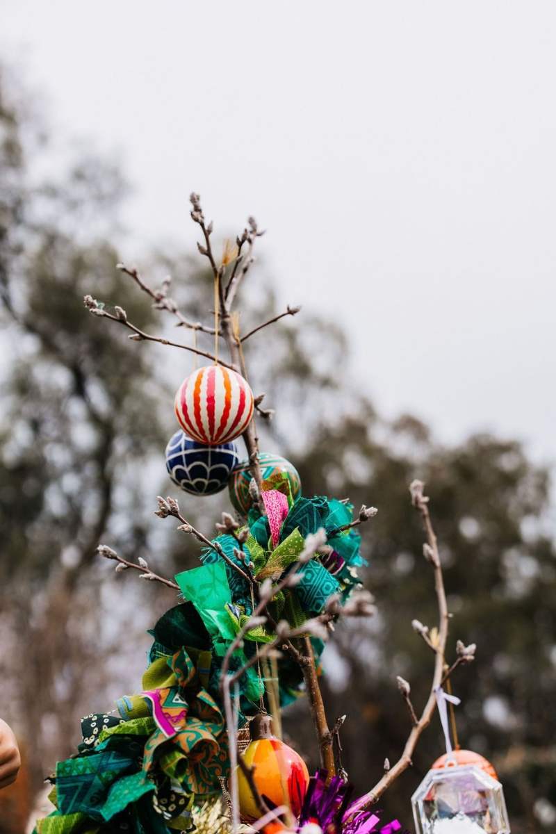 Decorative outdoor ornament with colorful balls and green fabric against a blurred natural background
