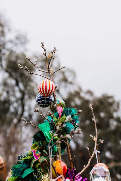 Decorative outdoor ornament with colorful balls and green fabric against a blurred natural background