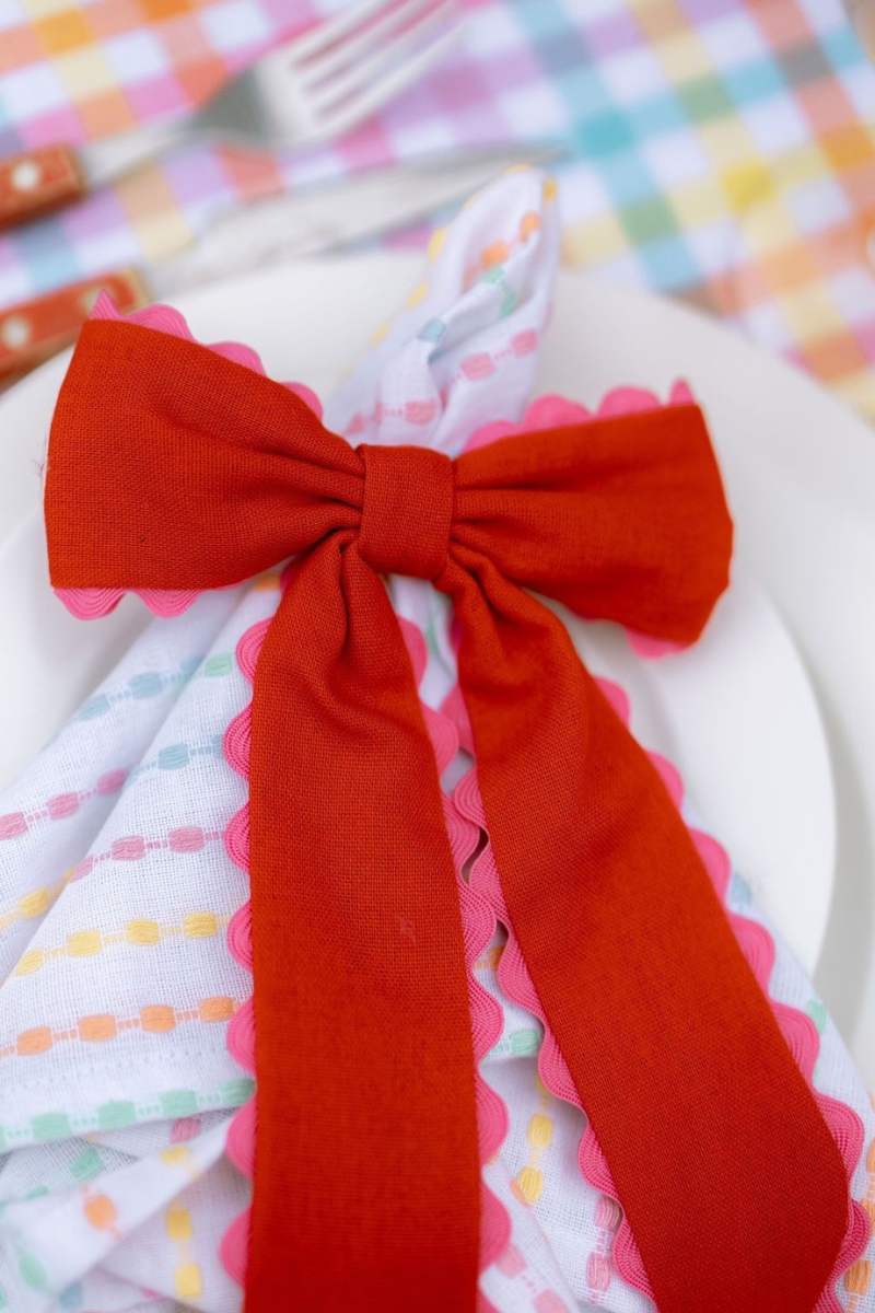 Red bow on a colorful plate with a checkered tablecloth in the background