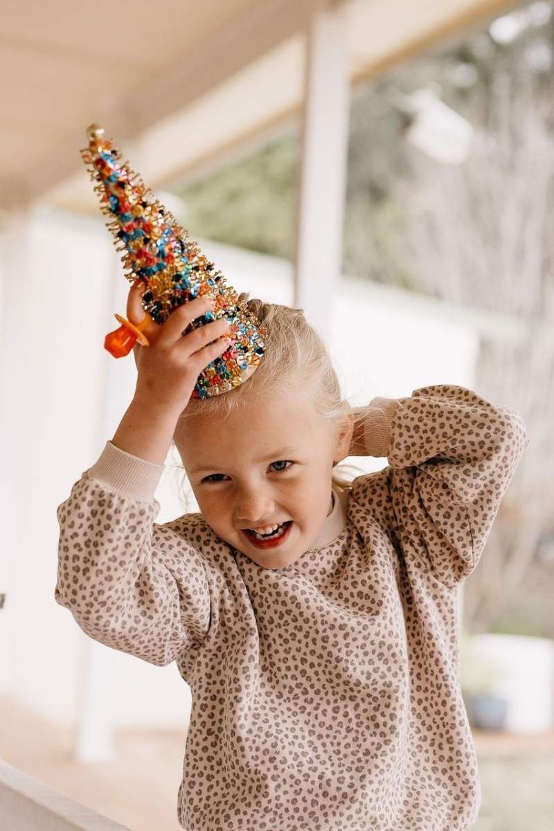 Child wearing a colorful unicorn horn headband indoors
