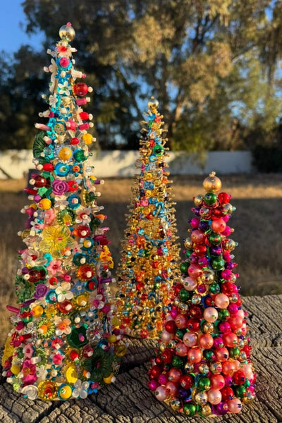 Colorful beaded Christmas trees on a wooden surface with a natural background