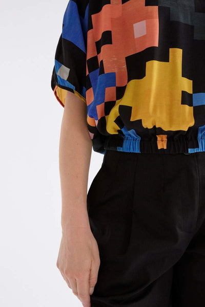 Person wearing a colourful pixel-patterned ELK top on a white background