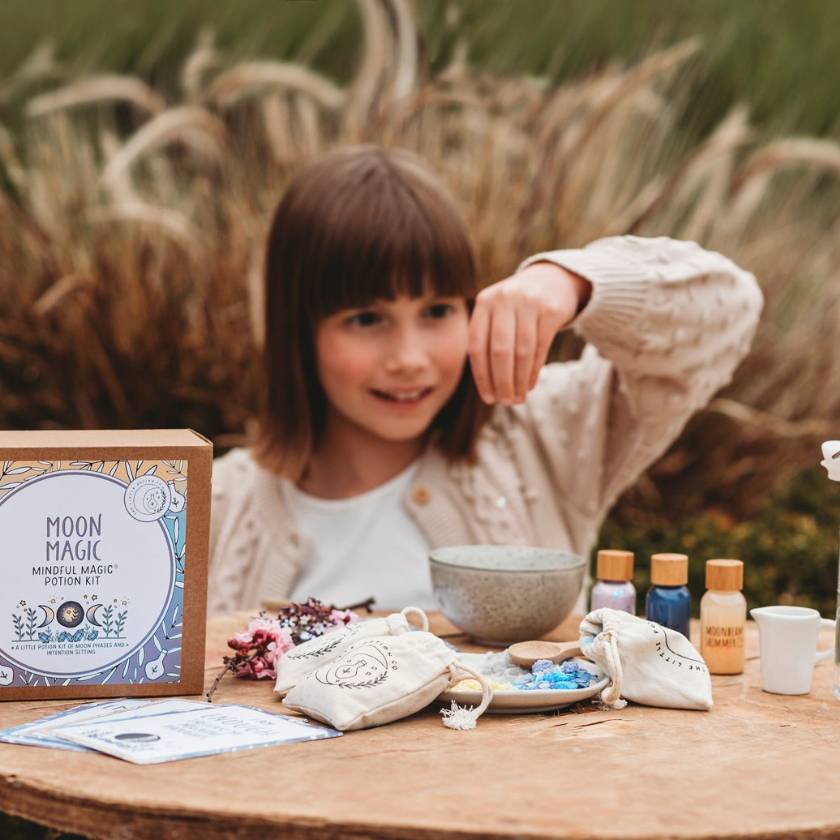 Child with a 'Moon Magic' kit on a wooden table outdoors