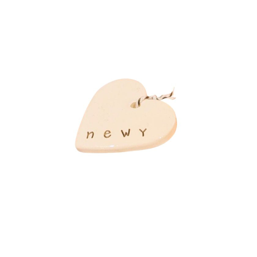 Newy Heart Tag by Caroline C with small ribbon. Made from ceramic with NEWY printed on the edge.