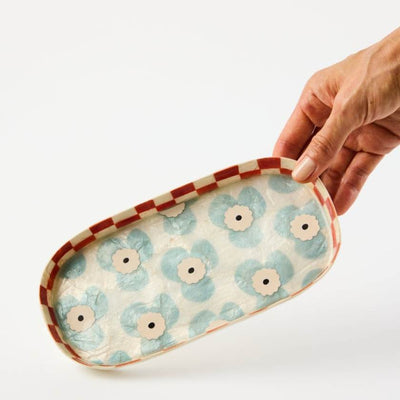 Hand holding a floral-patterned tray with a white background