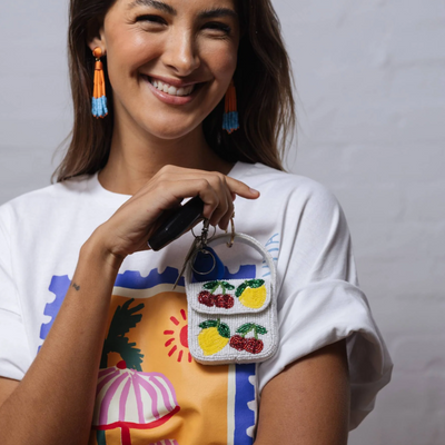 Woman holding a colorful beaded handbag with a plain background by Zoda 