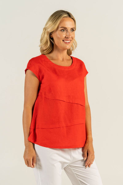 A stylish woman confidently wears See Saw's classic red linen top, showcasing the chic round scooped neckline and short capped sleeves.