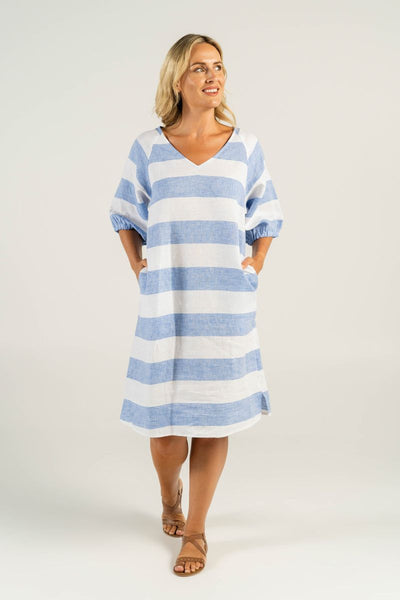 A model exudes effortless charm in the V-Neck Chambray Dress, featuring a crisp white and blue pattern. The flattering V-neck and slightly puffy sleeves add a touch of femininity to this versatile and chic ensemble.