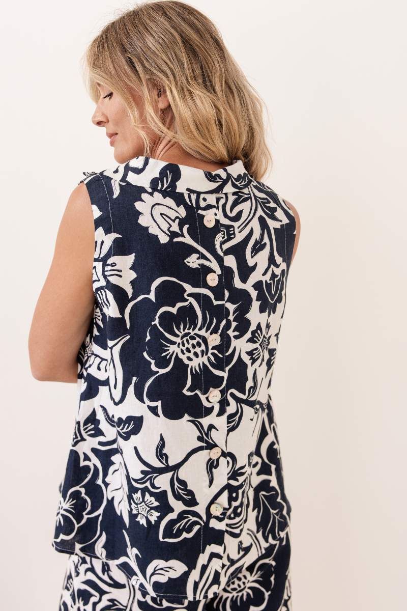 Woman wearing a sleeveless navy floral top and pants against a white background