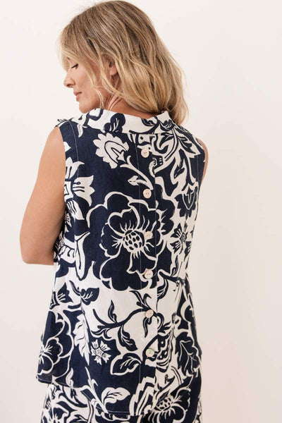 Woman wearing a sleeveless navy floral top and pants against a white background