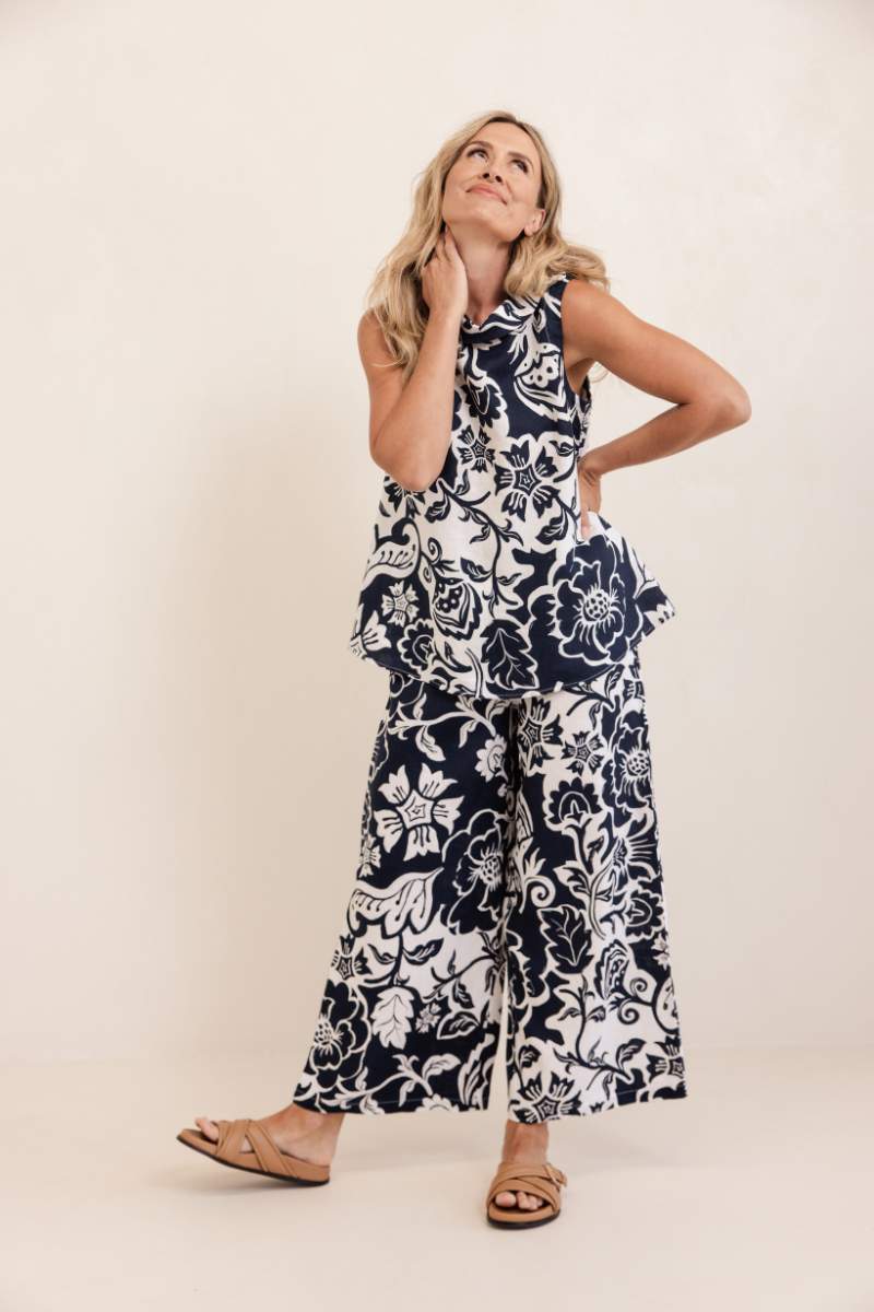 Woman wearing a navy and white floral top and pants on a beige background