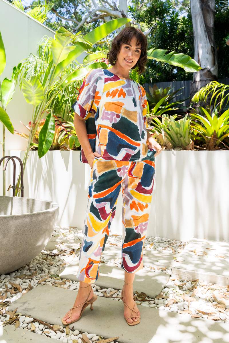 Woman in a colourful outfit standing outdoors with plants in the background