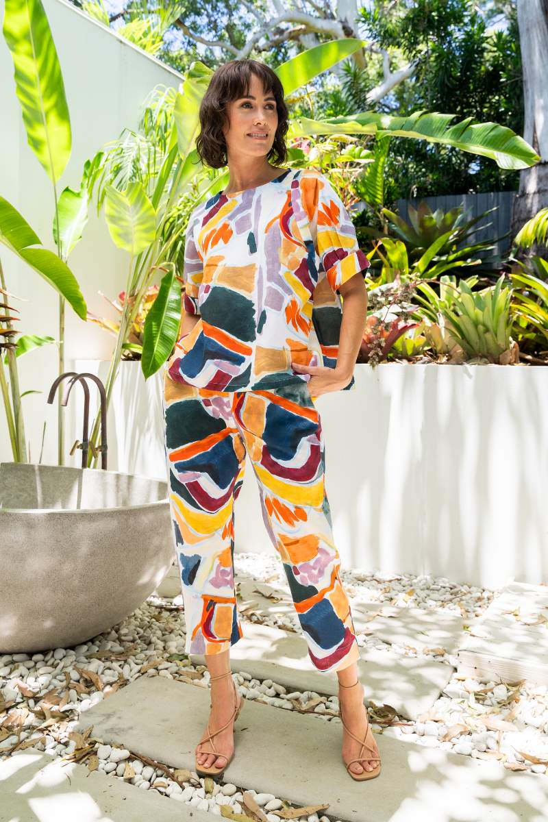 Woman in a colourful outfit standing outdoors with plants in the background