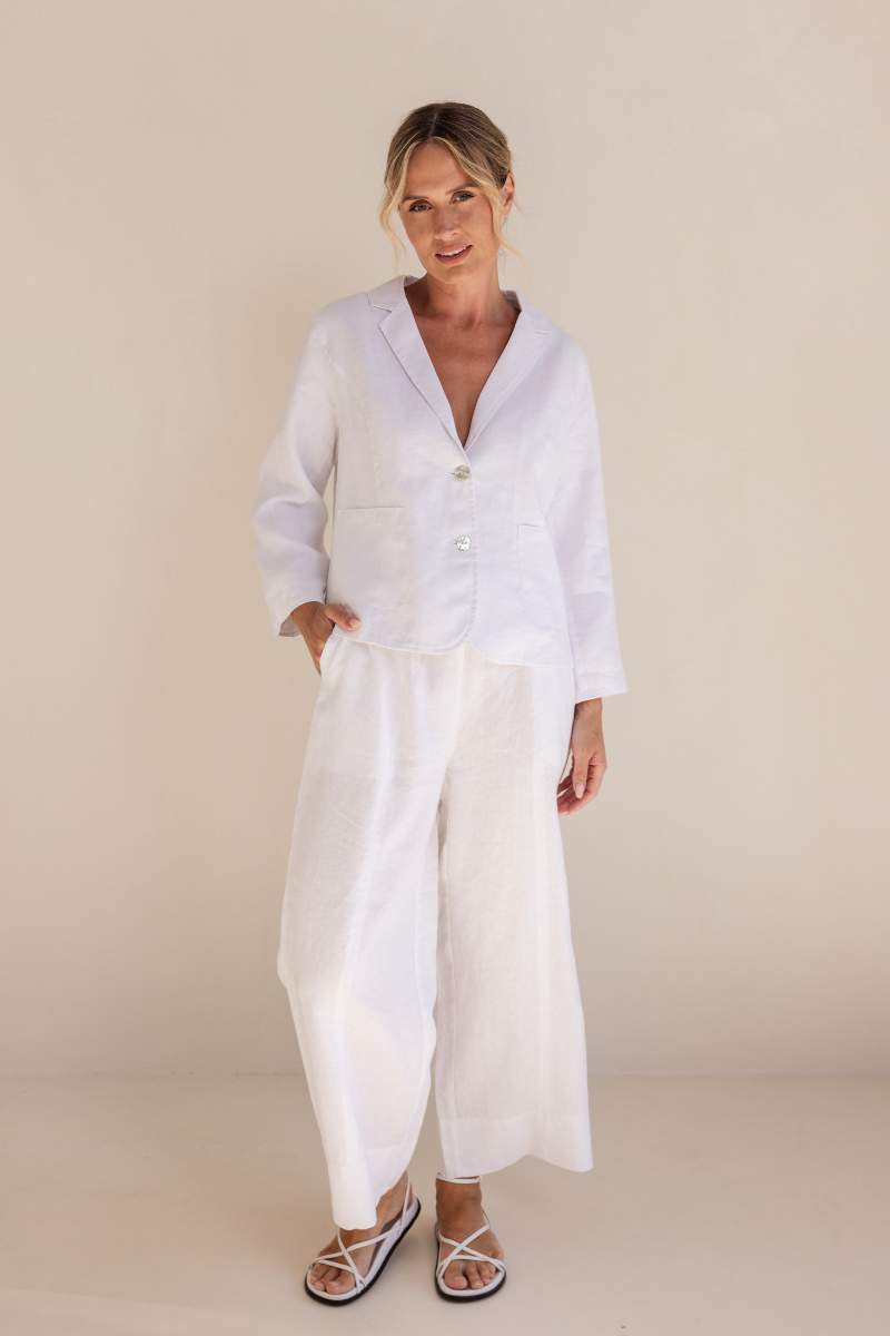 Woman wearing a white outfit against a beige background
