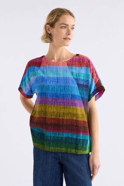 Woman wearing a colourful ELK striped shirt against a white background