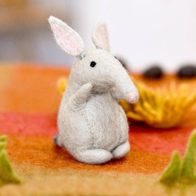 Small gray bilby figurine on a colorful fabric background