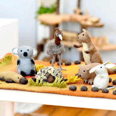 Set of felt animal toys on a felt landscape with a blurred background