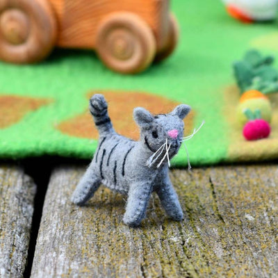 Felted gray cat toy on a wooden surface with a colorful felt board in the background