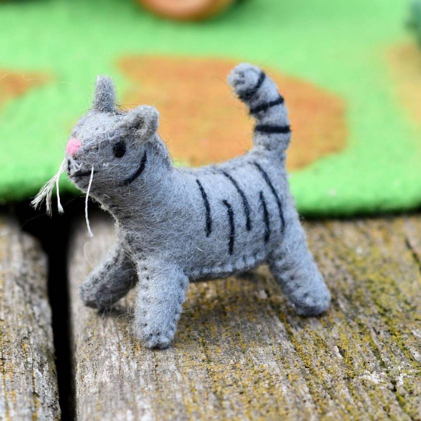 Gray toy cat with black stripes on a textured surface