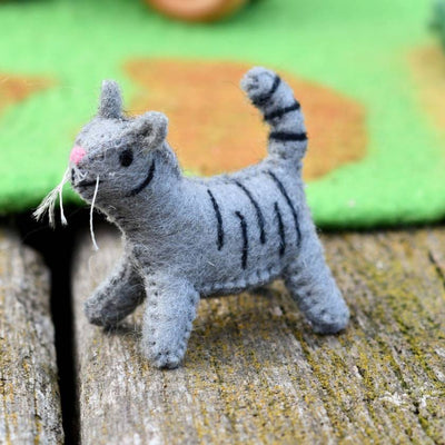 Gray toy cat with black stripes on a textured surface