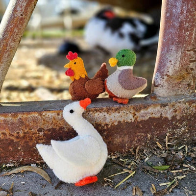 Toy chickens and a duck on a rusted metal surface with a blurred background