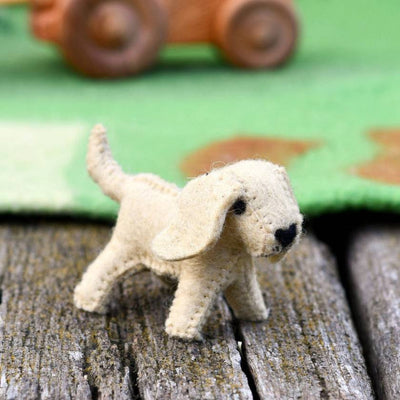 Small dog figurine on a wooden surface with a blurred toy car in the background
