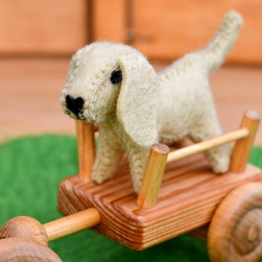 Small white dog toy on a wooden cart with a blurred background