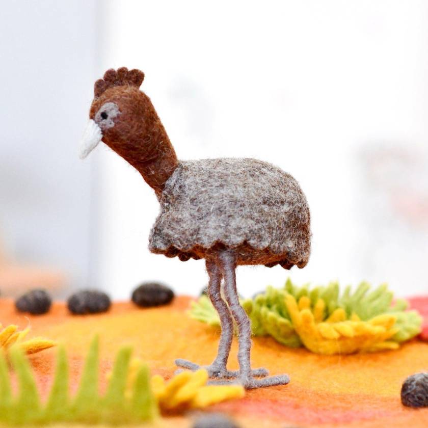 Small model of an emu standing on a colorful surface with blurred background