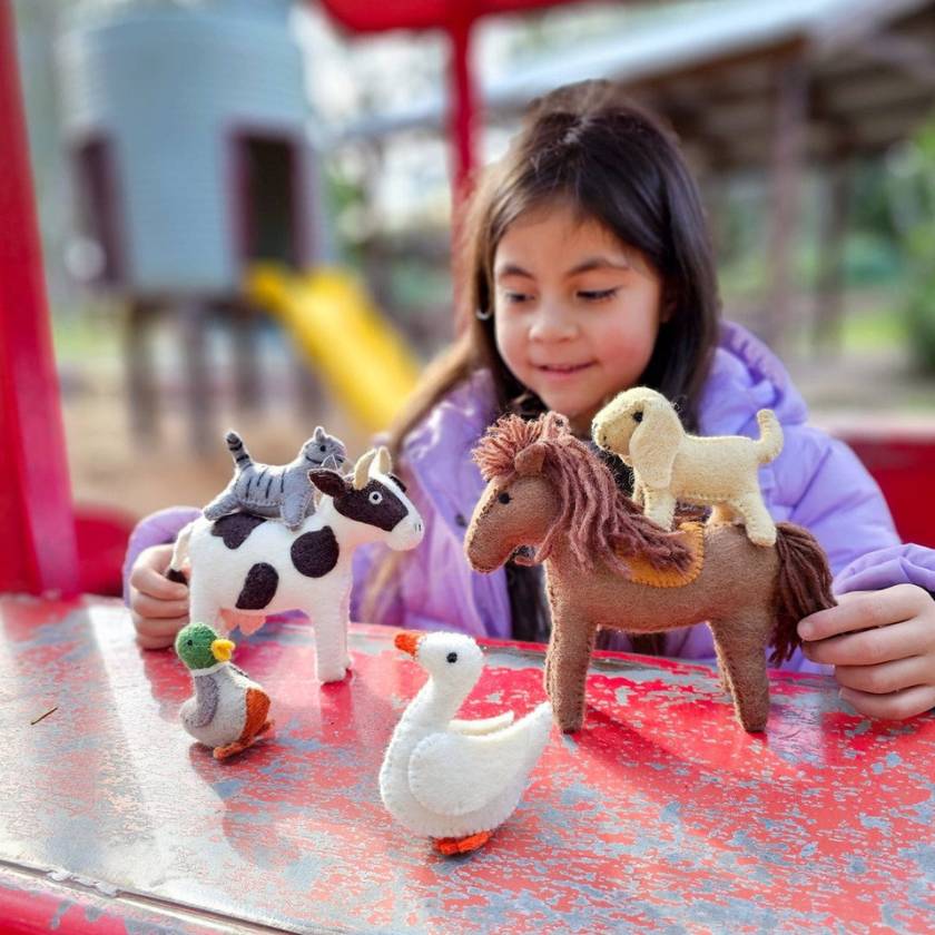 Child playing with toy animals on a red surface outdoors