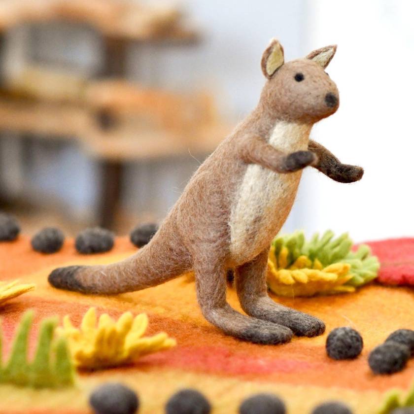 Felted kangaroo toy on a cake with autumn-themed decorations